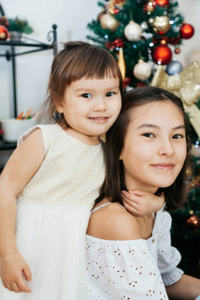 istock Two sisters with gifts sitting near Christmas tree 1292458079