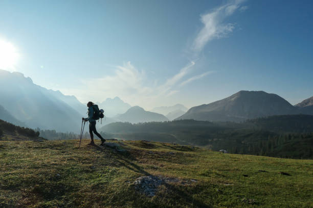 Armentarola - A woman enjoying an early morning in Italian Dolomites A woman enjoying an early morning in Italian Dolomites. The valley below is shrouded in morning haze. In the back there are high mountain chains. Sun slowly rising above the peaks. Golden hour catinaccio stock pictures, royalty-free photos & images