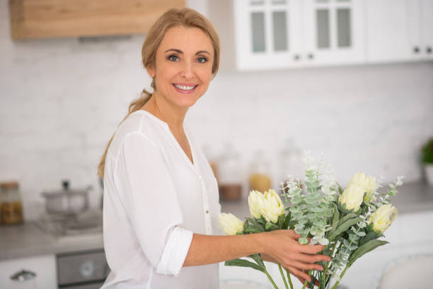istock Woman decorating the kitchen with white beautiful flowers 1292465101