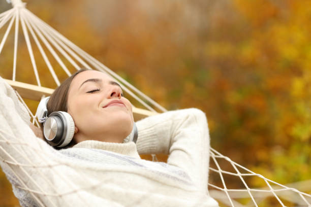 mujer relajada escuchando música con auriculares en la hamaca - mountain stream fotografías e imágenes de stock