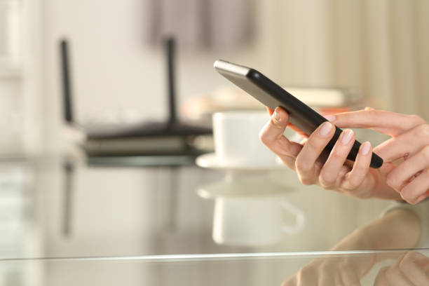 istock Woman hand using wifi on phone with a router in background 1292470902