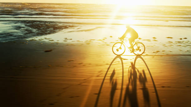 Man Casting Long Shadow Cycling on Oregon Beach - Drone Shot