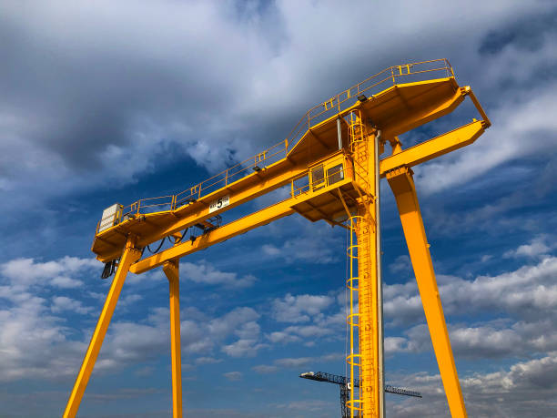 Gantry crane opposite cloudy sky. Industrial lifting machinery. Hoist, winch Gantry crane opposite cloudy sky. Industrial lifting machinery. Hoist, winch. gantry crane stock pictures, royalty-free photos & images