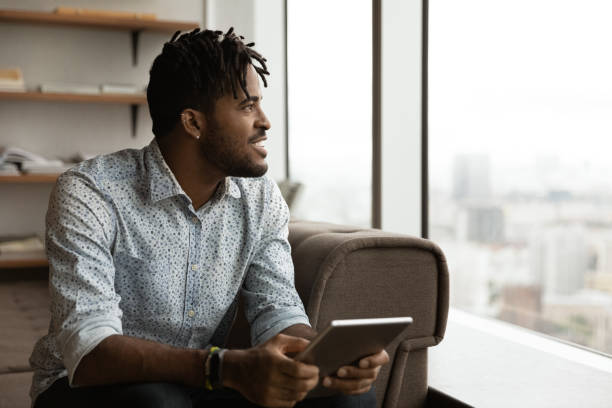 istock Smiling biracial man use tablet thinking at home 1292475547