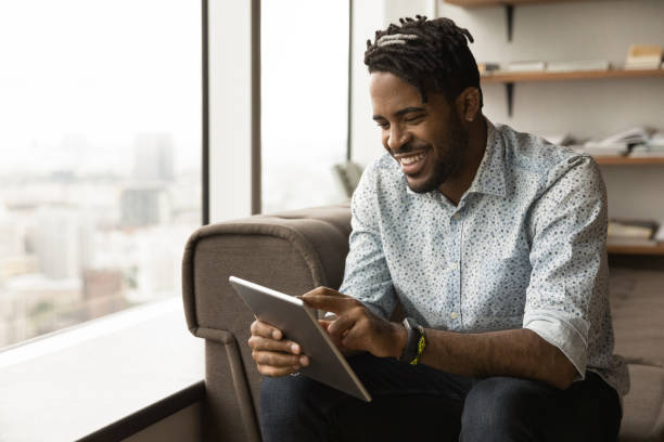 istock Smiling biracial man use tablet relaxing at home 1292475548