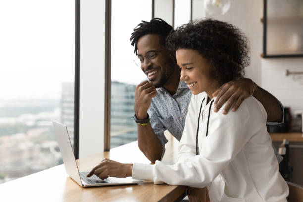 Happy biracial couple use laptop at home together