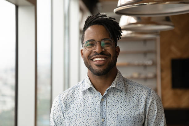 Headshot portrait of smiling biracial man posing Profile picture of smiling young African American man in glasses pose in own home apartment. Close up headshot portrait of happy millennial biracial male renter or tenant in spectacles show optimism. 25 year old man portrait stock pictures, royalty-free photos & images