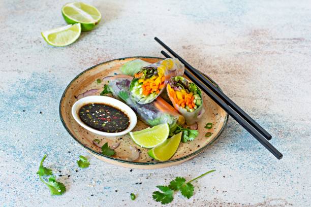 istock Fresh Asian appetizer Spring rolls (Nem) made from rice paper and raw vegetables and herbs with hot sauce on a light blue background. Vietnamese Food 1292477416
