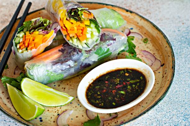 istock Fresh Asian appetizer Spring rolls (Nem) made from rice paper and raw vegetables and herbs with hot sauce on a light blue background. Vietnamese Food 1292477434