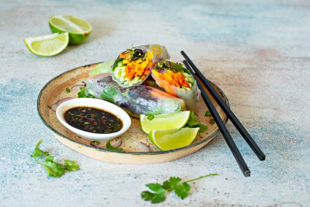 istock Fresh Asian appetizer Spring rolls (Nem) made from rice paper and raw vegetables and herbs with hot sauce on a light blue background. Vietnamese Food 1292477435