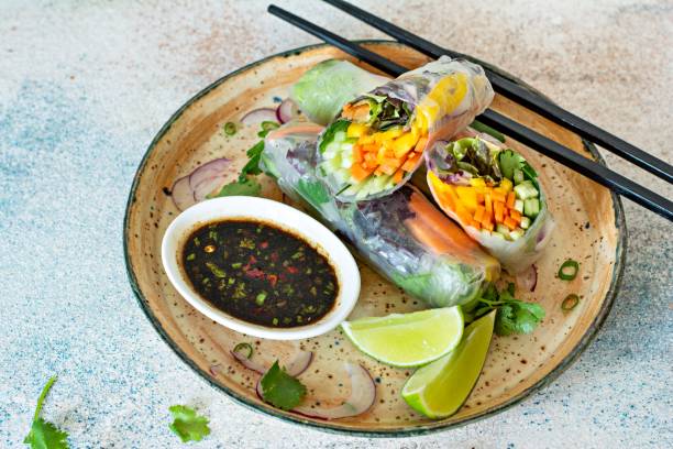 istock Fresh Asian appetizer Spring rolls (Nem) made from rice paper and raw vegetables and herbs with hot sauce on a light blue background. Vietnamese Food 1292477441