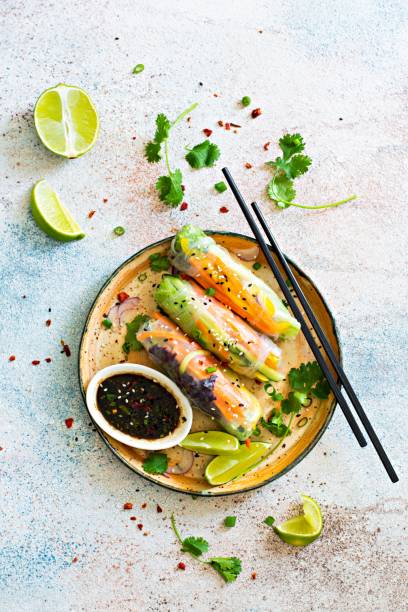 istock Fresh Asian appetizer Spring rolls (Nem) made from rice paper and raw vegetables and herbs with hot sauce on a light blue background. Vietnamese Food 1292477448