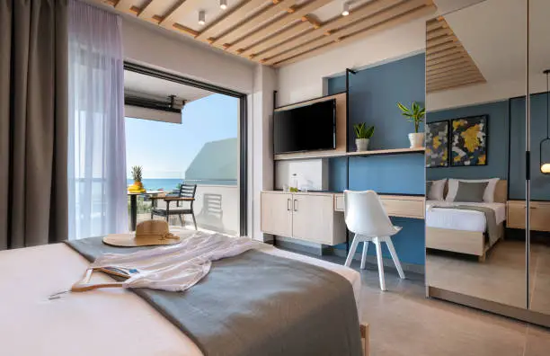 Photo of Modern loft style bedroom with metal details, wooden furniture, mirror wardrobe, abstract decor. Hotel apartment with sea view balcony, open air French window terrace