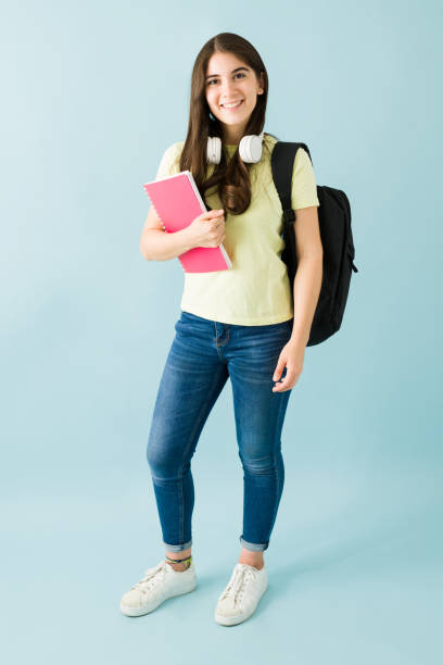 istock Happy university student carrying a backpack, headphones and a notebook 1292484712