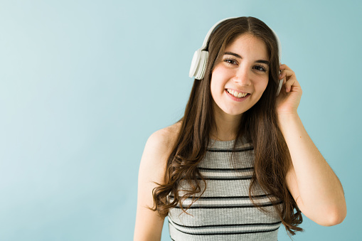 Beautiful young caucasian woman listening to music with headphones and smiling to the camera