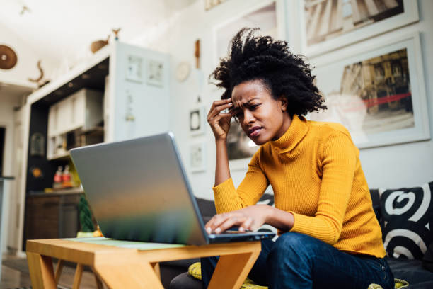 African American woman working from home Stressed out African American female freelancer working from home using her laptop and encountering some problems concerning her business nettle stock pictures, royalty-free photos & images