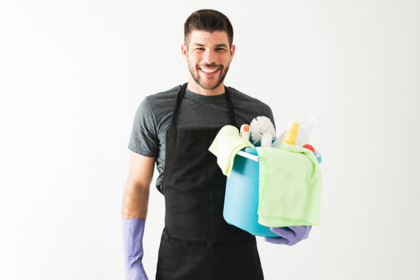 Smiling man in his 20s carrying some cleaning products