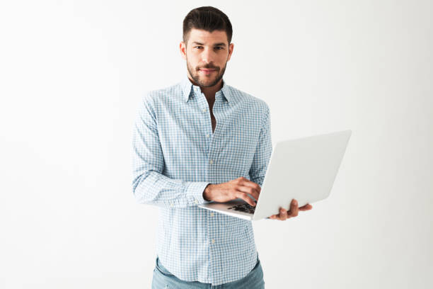 istock Latin young man is standing and working on a laptop 1292488388