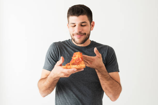 istock Man in his 20s savoring and looking at a pepperoni pizza 1292488475