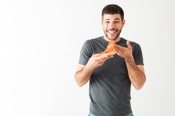 giovane ragazzo ispanico che sta per prendere un boccone di una fetta di pizza - man eating foto e immagini stock