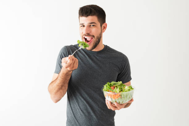 istock Fit young man taking a bite of a green salad 1292488489