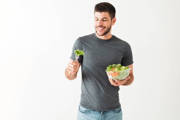 istock Healthy young guy eating a green salad with a fork 1292488492