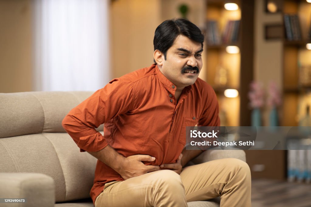 Mature man sofa sitting at home - stock photo Indian, Indian ethnicity, lifestyle, real people, mature, sofa, Stomachache Stock Photo