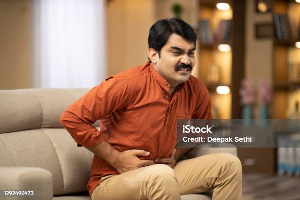 Mature Man Sofa Sitting At Home Stock Photo Stock Photo - Download Image Now - Stomachache, India, Indian Ethnicity