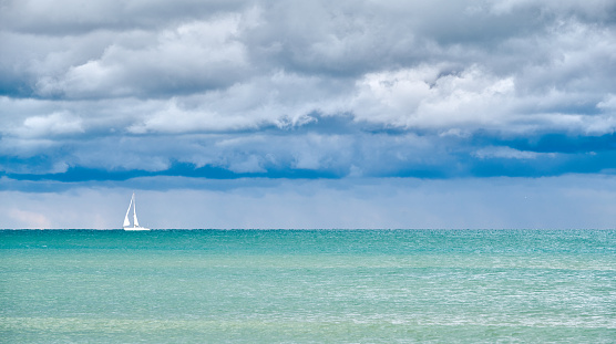 Single Sailboat close to Venice, with calm sea before the storm, under a heavy cloudy sky