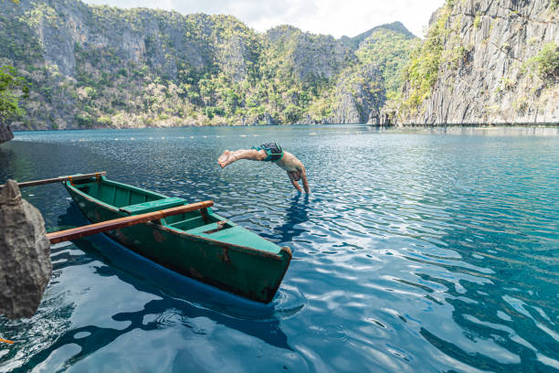 jovem adulto mergulhando fora do barco enquanto viajava nas filipinas - mergulho autónomo - fotografias e filmes do acervo