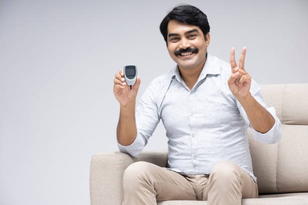 Mature man sitting sofa at white background, stock photo Indian, Indian ethnicity, lifestyle, real people, mature, background, sofa, man showing peace sign stock pictures, royalty-free photos & images