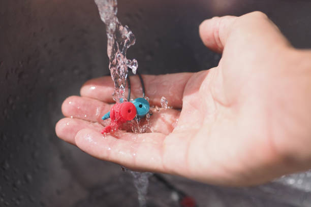 Crop image. Hand washing earplugs in the sink.