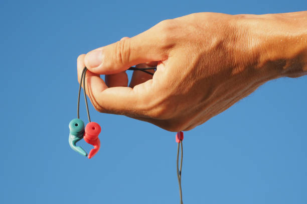 Crop image. Hand holding ear protection plugs for swimming and surfing.