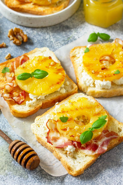 gesundes frühstück oder snacks aus nächster nähe. toast mit karamellisierter ananas, speck, nüssen und ricotta auf schieferhintergrund. - 24193 stock-fotos und bilder