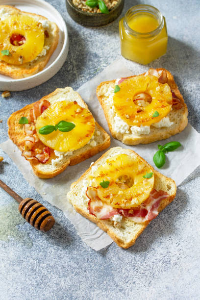 desayuno saludable o refrigerios. tostadas con piña caramelizada, tocino, nueces y ricotta sobre un fondo de pizarra. copiar espacio. - 24190 fotografías e imágenes de stock