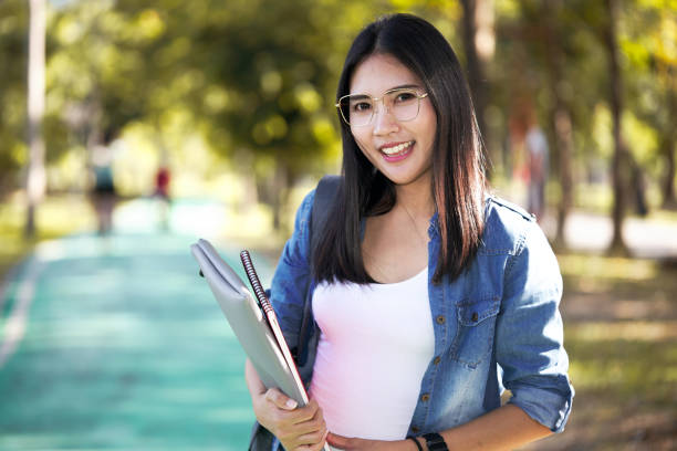 istock Asian female college student holds a book inside the university. 1292501861