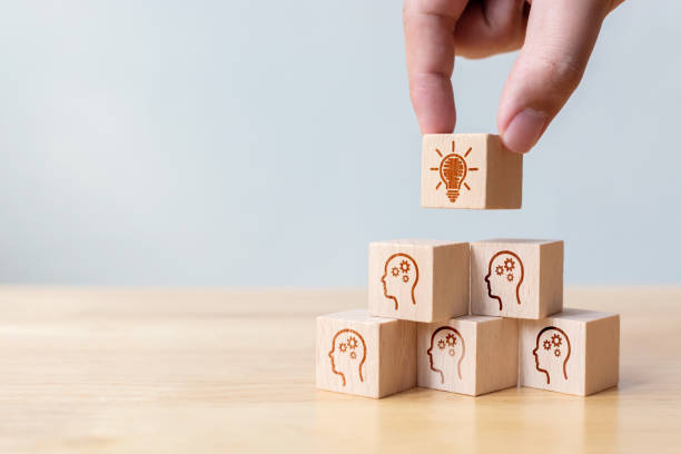 istock Concept creative idea and innovation. Hand picked wooden cube block with head human symbol and light bulb icon 1292503542