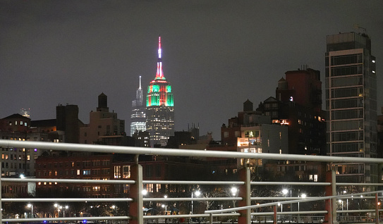 Night time shot taken from Hudson River Park in Greenwich Village of the Empire State Building illuminated in red and green light for Christmas.