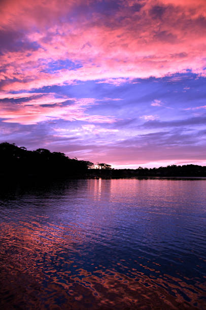 Stunning pink cumulus cloud sunset waterscape with water reflections. Nautical dusk at Gosford, NSW, Australia.