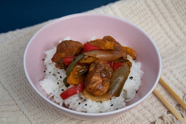 istock Pink bowl with cooked rice and plaid chicken decorated with black sesame with background 1292511521