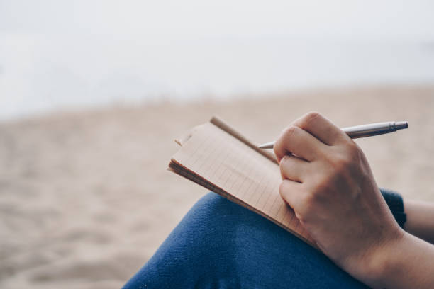 istock Woman hand writing down in small white memo notebook for take a note not to forget or to do list plan for future. 1292514166