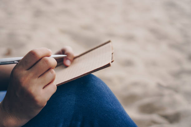 istock Woman hand writing down in small white memo notebook for take a note not to forget or to do list plan for future. 1292514181
