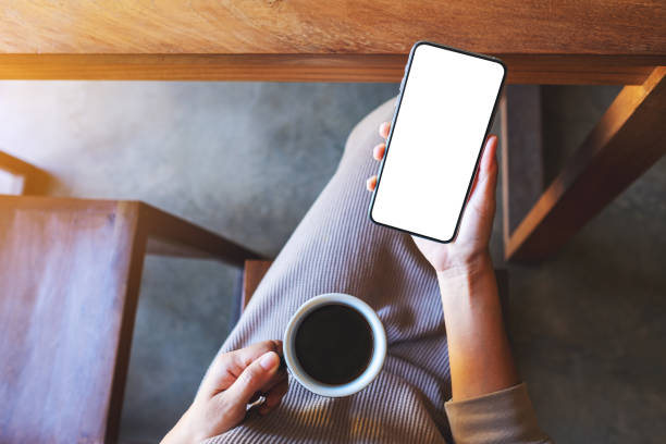 istock a woman holding mobile phone with blank white desktop screen while drinking coffee 1292517700