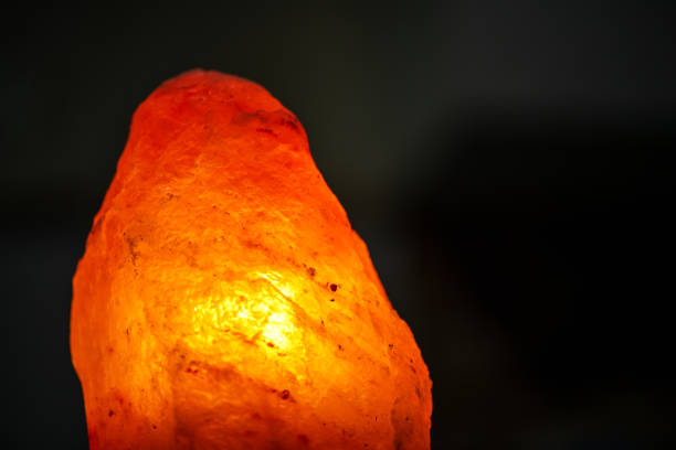 istock Salt lamp on a black background. Rock orange, close up. Blurred background 1292519789