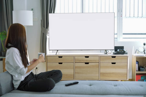 istock Woman Watching white screen TV While Relaxing On Sofa. White screen TV for graphic montage. 1292527349