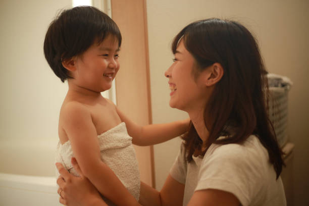 genitore e figlio che pulivano il corpo - bathtub asian ethnicity women female foto e immagini stock