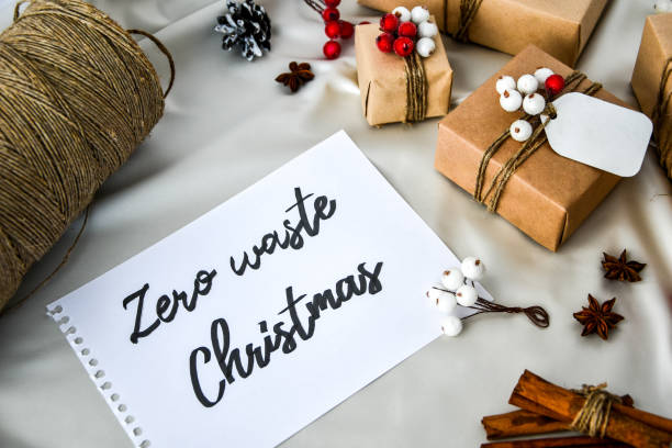 istock Zero waste Christmas text with presents with decorations on champagne colored silk background. Copy space. Eco friendly packed gift with tags from craft cardboard 1292529792