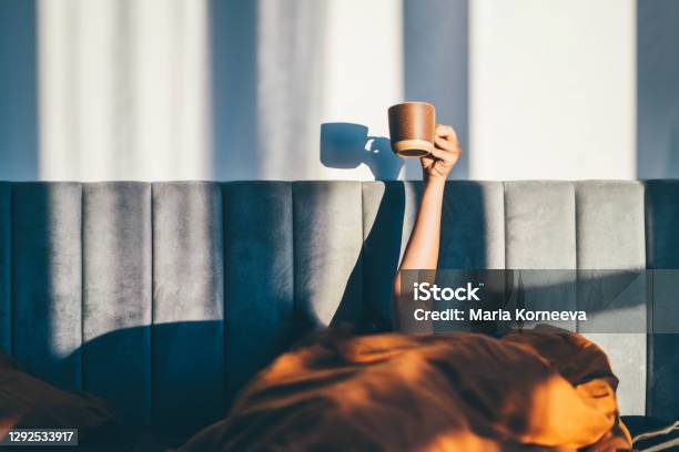 Hand Holding A Cup Of Coffee While Lying On Bed Morning Concept Stock Photo - Download Image Now