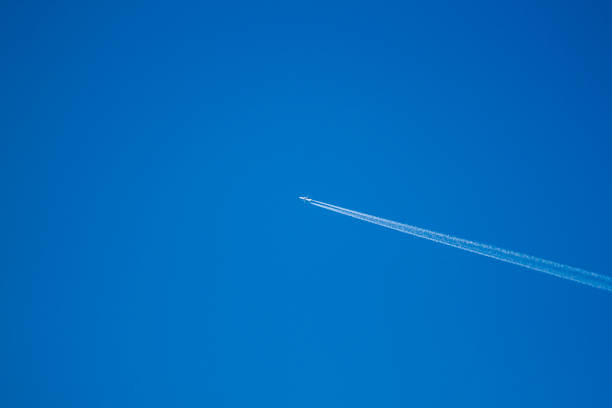 istock alone airplane flying in clear blue sky with white condensation trails 1292535090