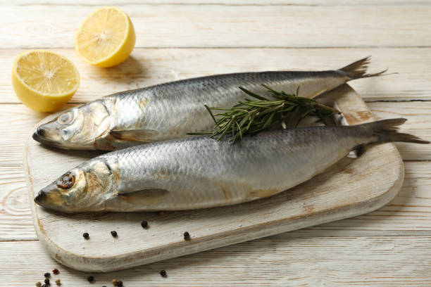 istock Board with fresh herring fish on white wooden background 1292535113